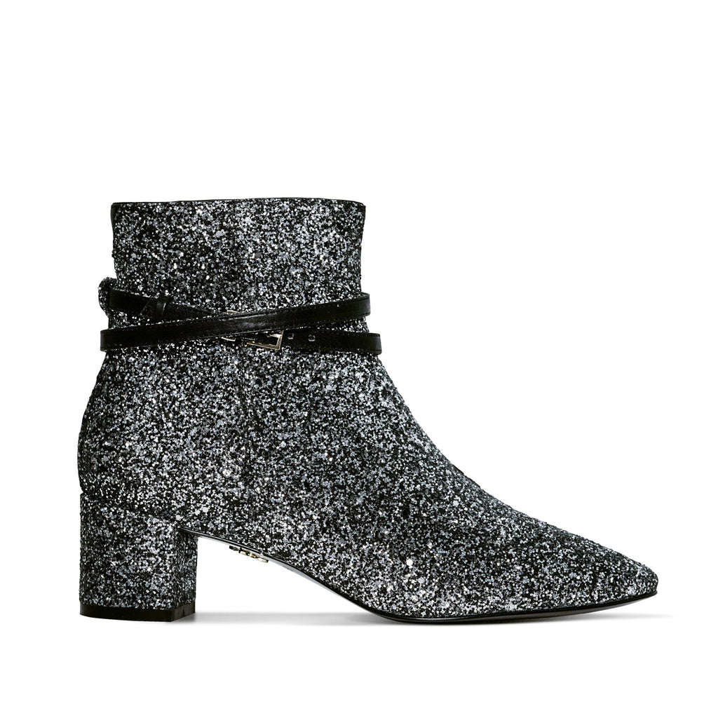 Silver glitter vegan ankle boot with block heel and contrast black patent buckle straps – stylish and eye-catching women's footwear for parties and special occasions.